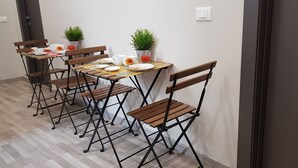 A dining area with a table set for four, surrounded by foldable chairs, with potted plants and a small table lamp. - Tre Stelle al Duomo (Catania)