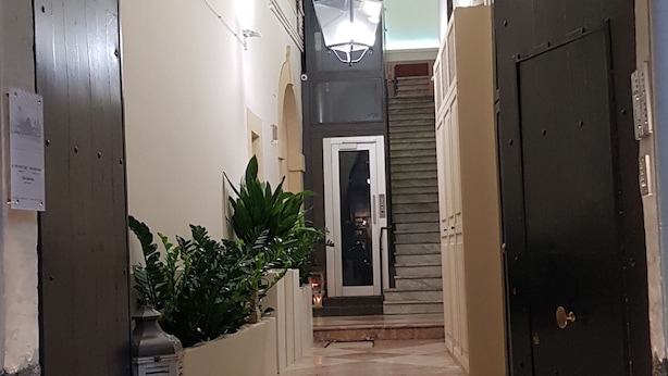 A grand entrance with a decorative metal archway, a staircase leading to a door, and a small lantern on the ground. - Tre Stelle al Duomo (Catania)