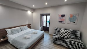 A modern bedroom with a bed, a black and white patterned sofa, and two abstract wall art pieces. - Tre Stelle al Duomo (Catania)
