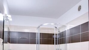 Un bany modern amb dutxa de vidre, vàter i rentapès.