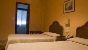 Una habitación de hotel con dos camas, una mesita de noche con teléfono y un cuadro en la pared.
