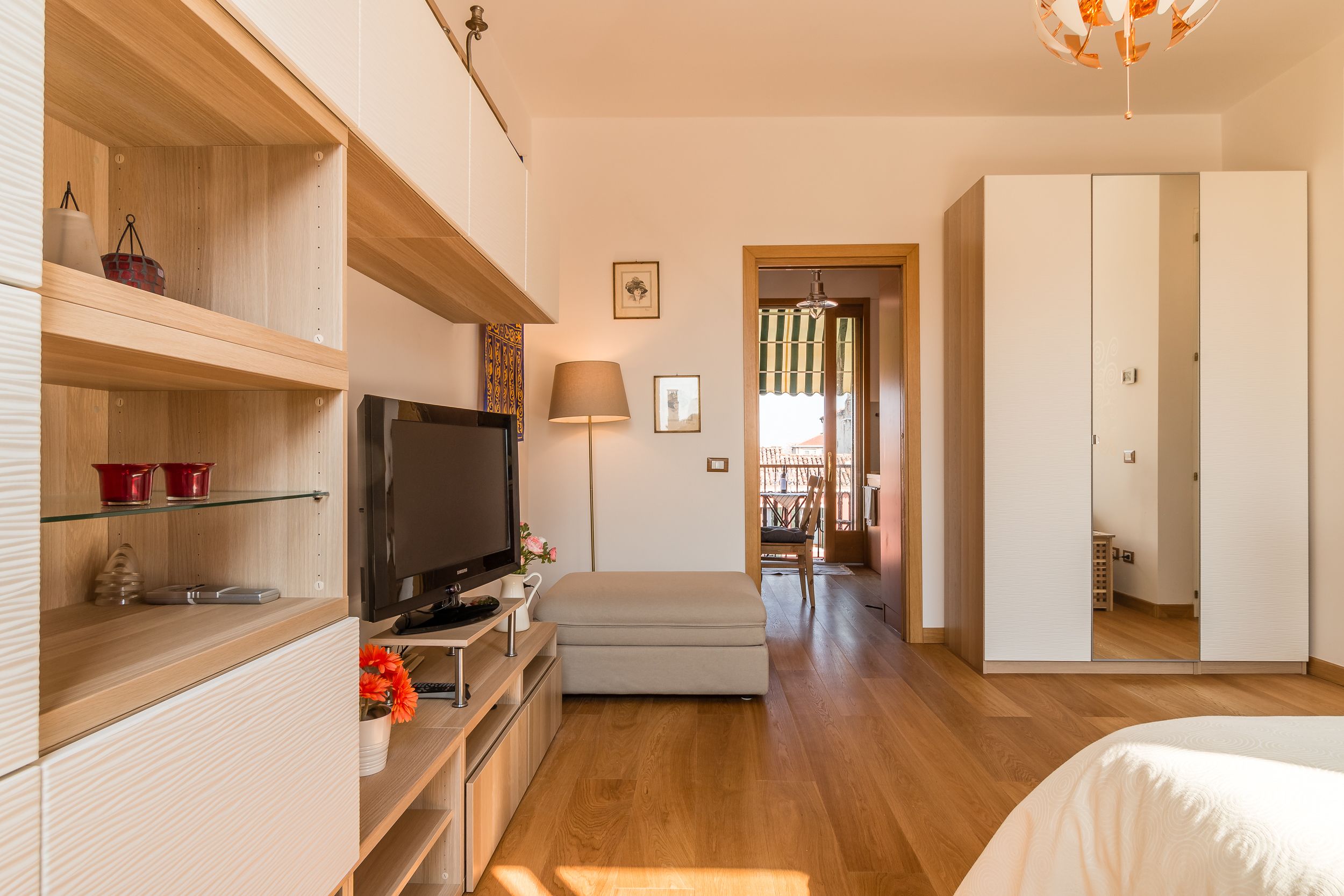 A modern bedroom with a TV, bedside table, and a wardrobe.