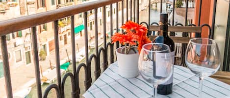 A balcony with a table set for two, featuring a bottle of wine and a glass.