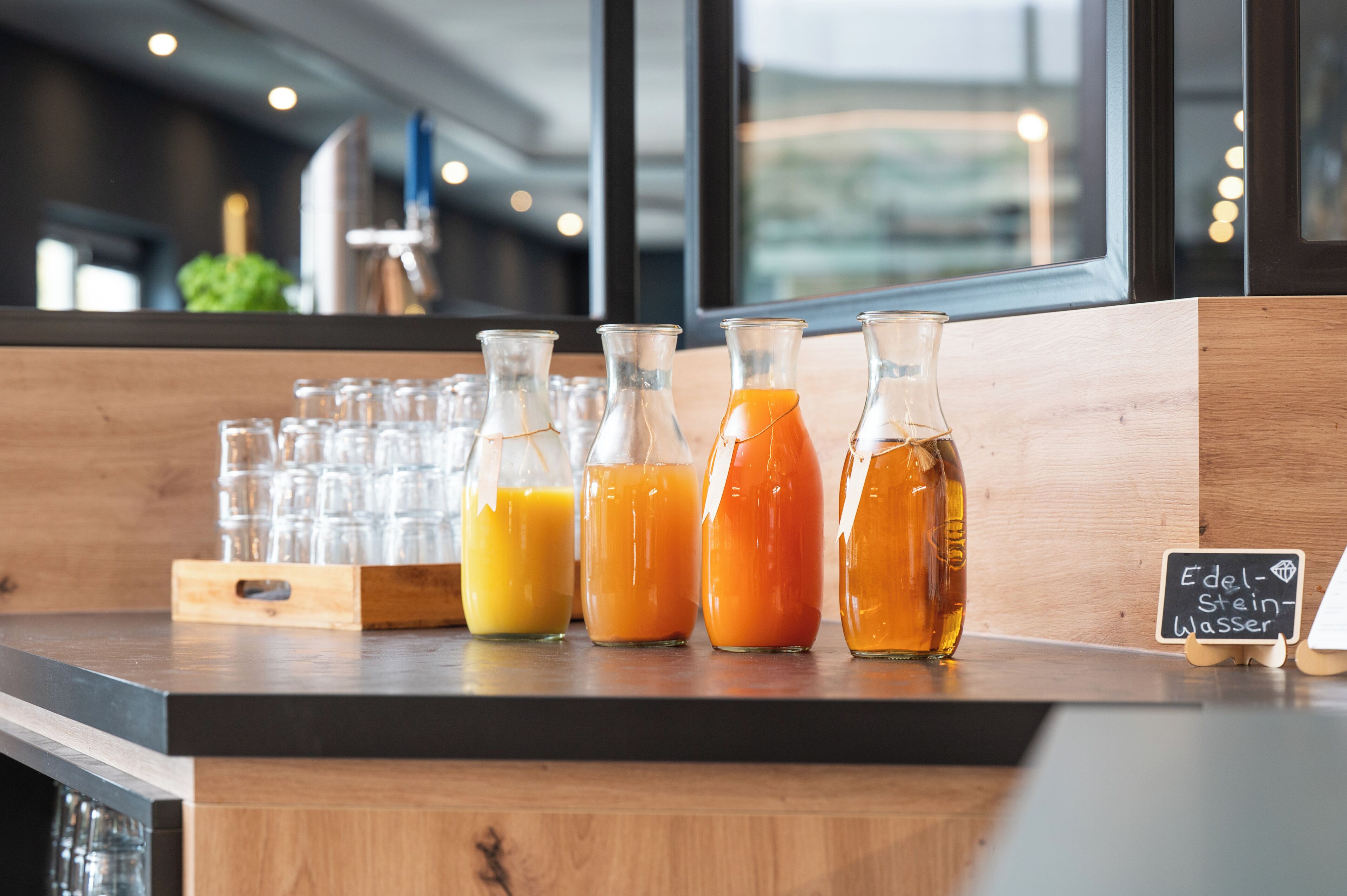 Zona de bar con varias botellas de bebidas, un menú en una pizarra y una barra de madera.