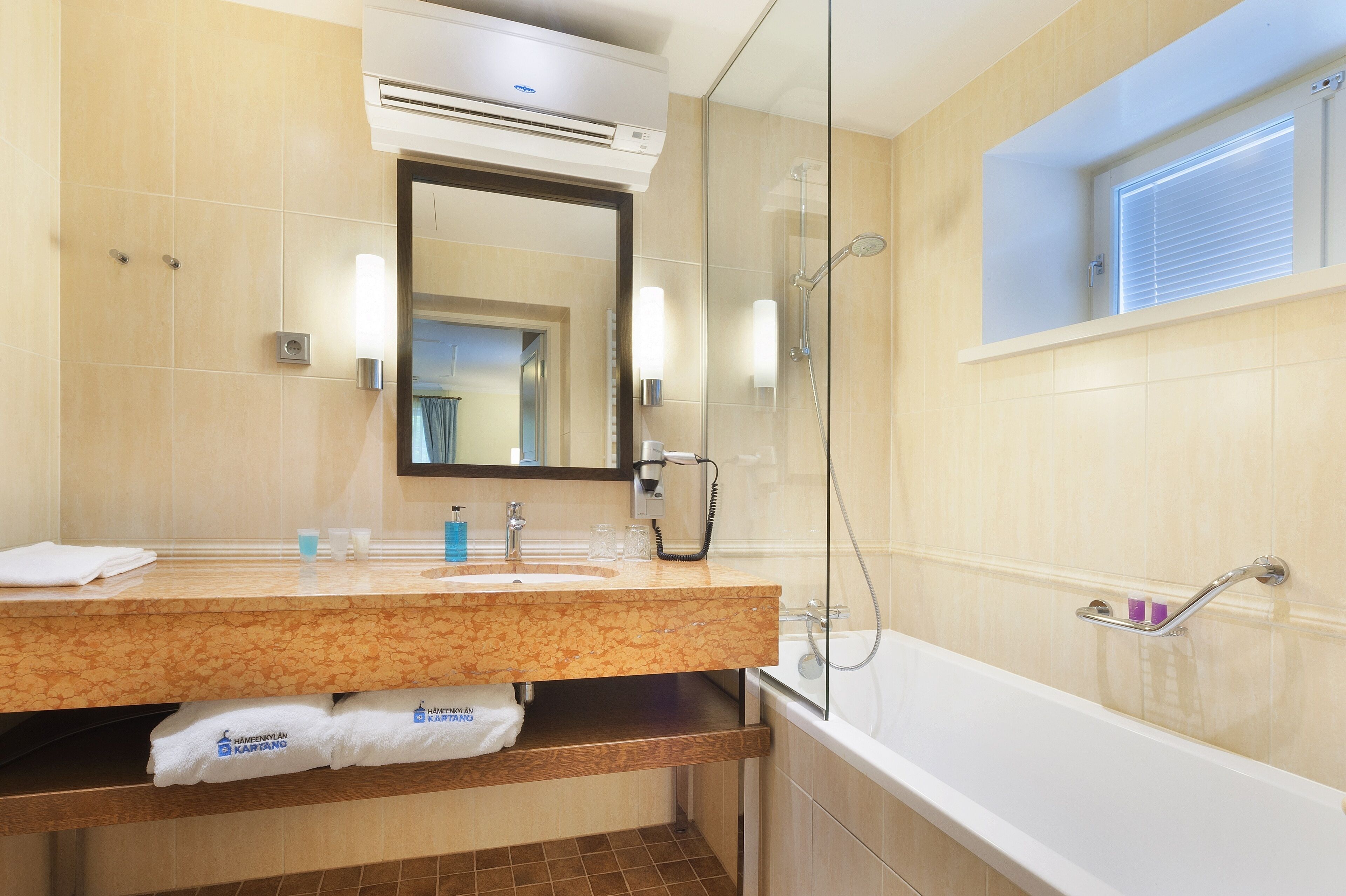 Un baño moderno con lavamanos de mármol, ducha con mampara de vidrio y una bañera.