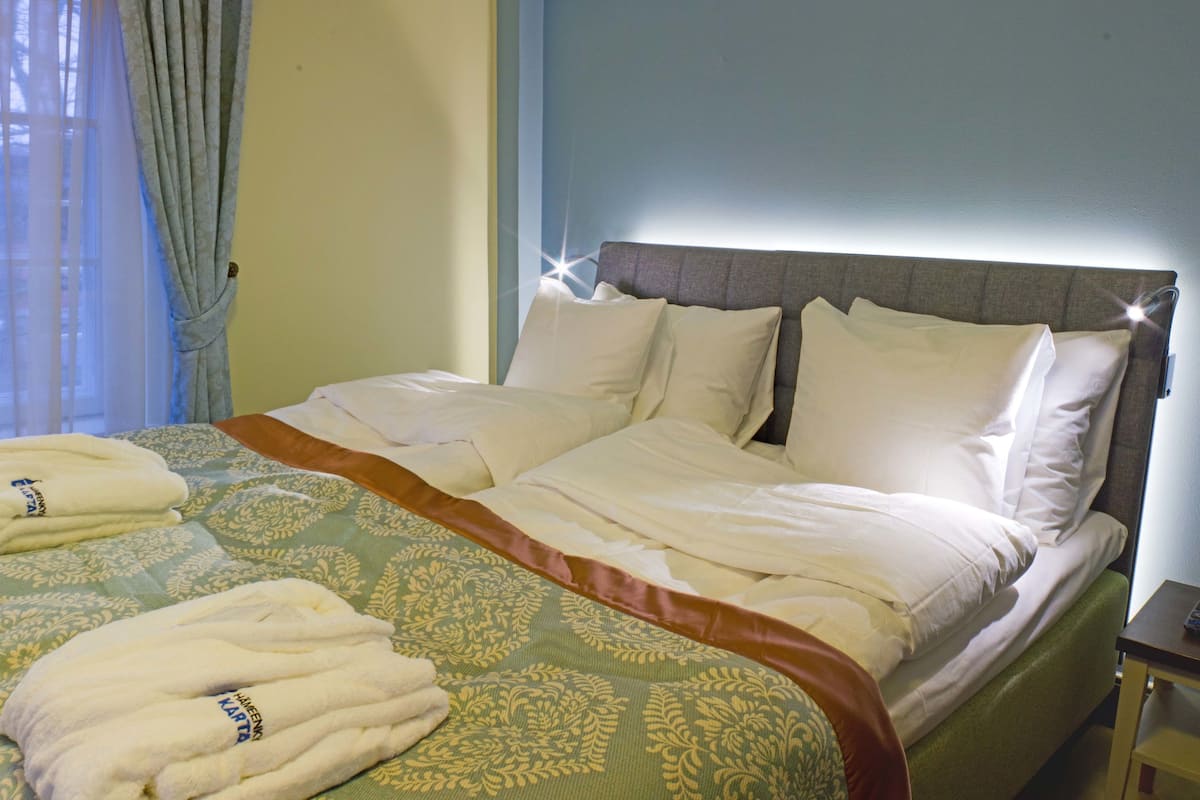 Una cama bien hecha con una colcha estampada y dos toallas dobladas al lado.
