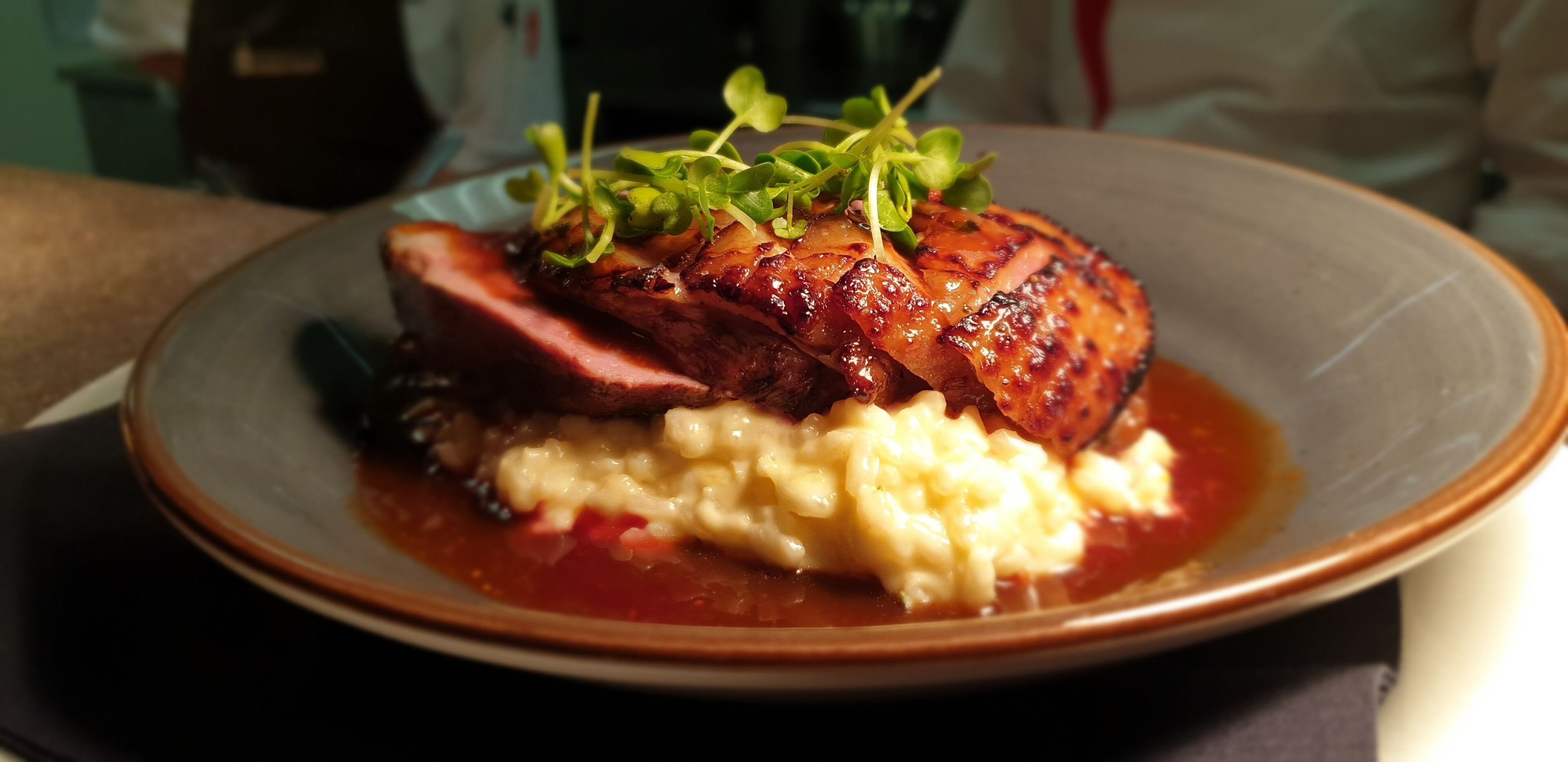 Une assiette de nourriture comprenant une viande laquée, de la purée de pommes de terre et une sauce rouge.