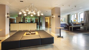 A modern lobby with a seating area, a reception desk, and a dining area. - Hämeenkylä Manor (Vantaa)