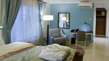 A hotel room with a bed, a desk, a chair, a mirror, and a wardrobe.