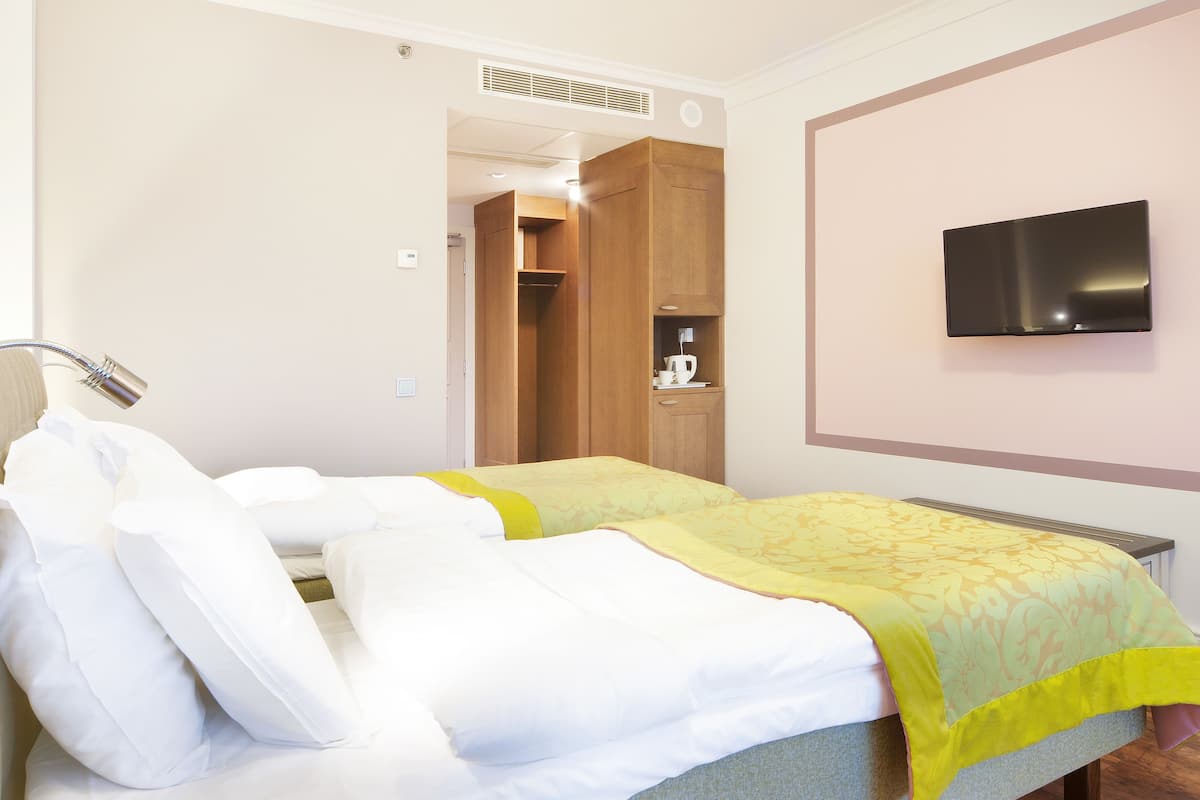Habitación de hotel con una cama, televisión y armario.