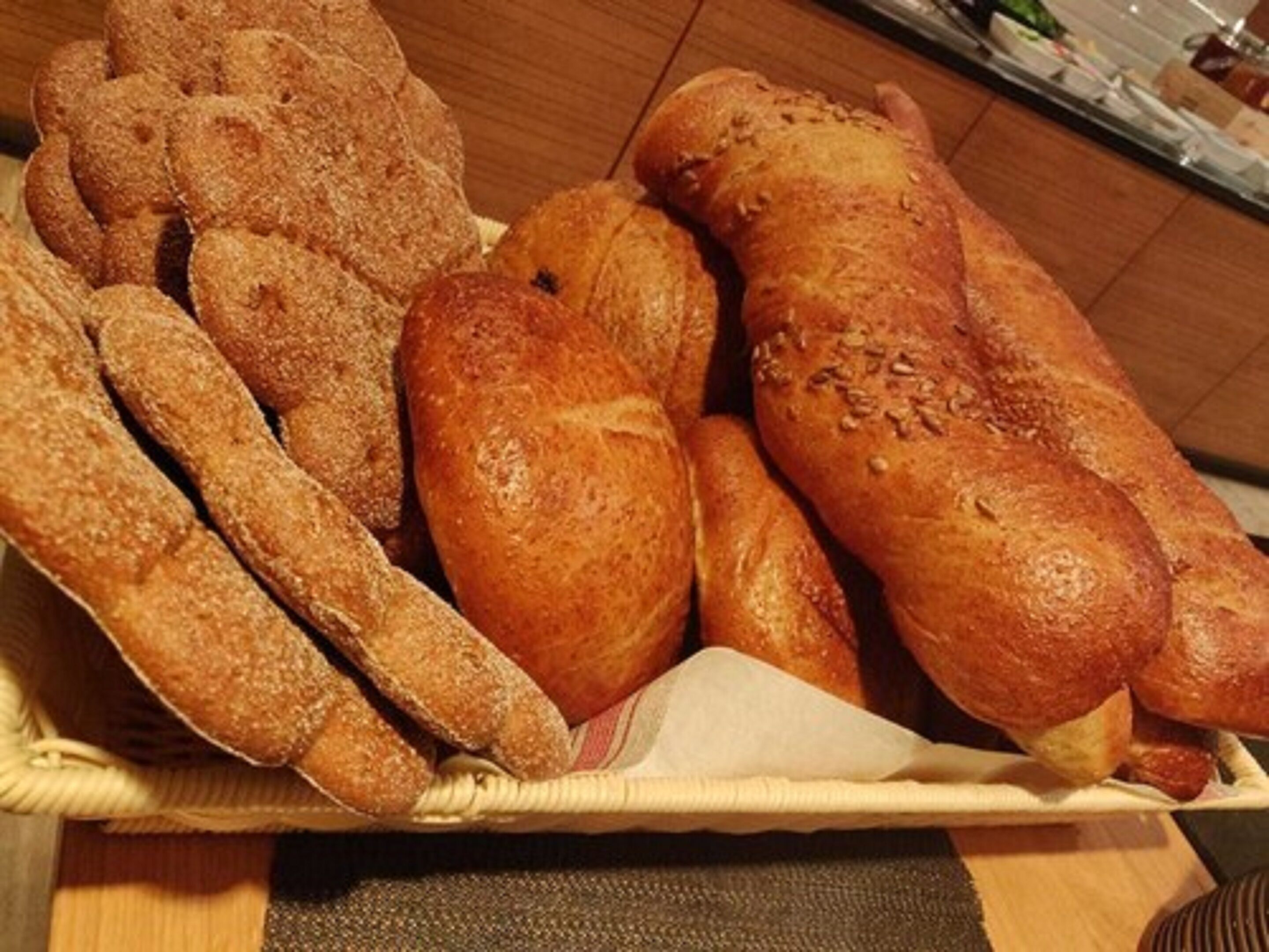 Una cesta con diversos panes, incluyendo baguettes y bollos.