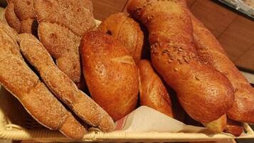Una cesta con diversos panes, incluyendo baguettes y bollos.