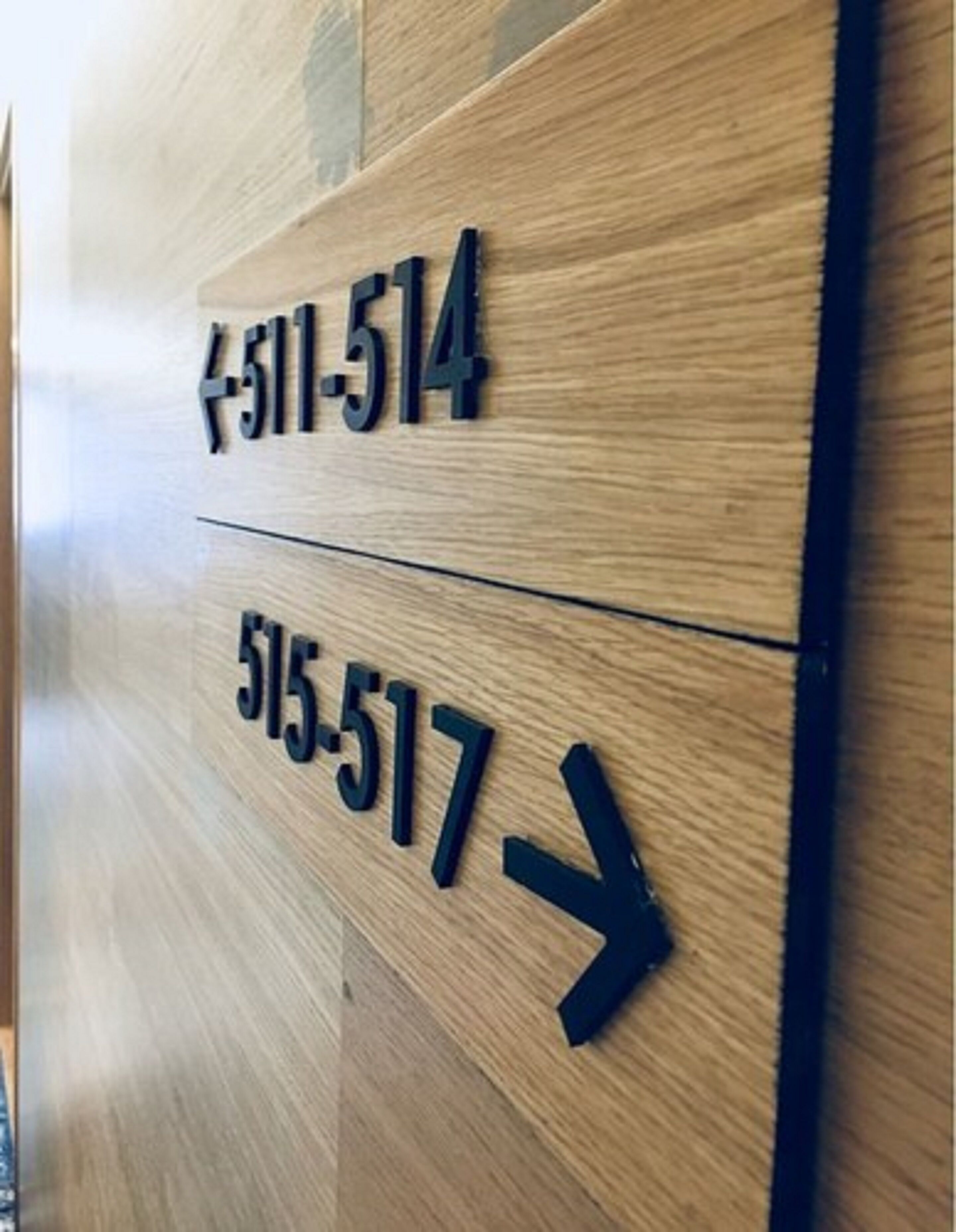 Pared de madera con flechas direccionales y números que señalan la ubicación de las habitaciones.