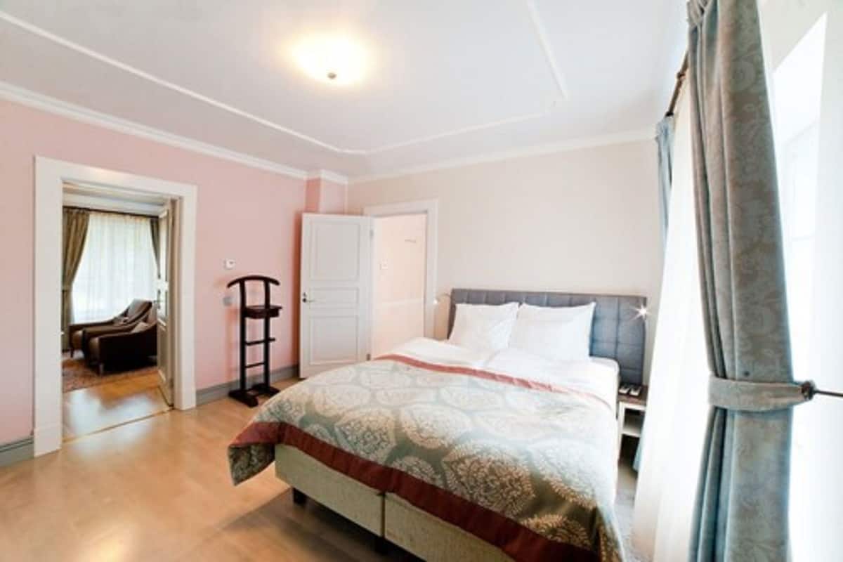 Un dormitorio con cama, armario, silla y puerta que da a otra habitación.