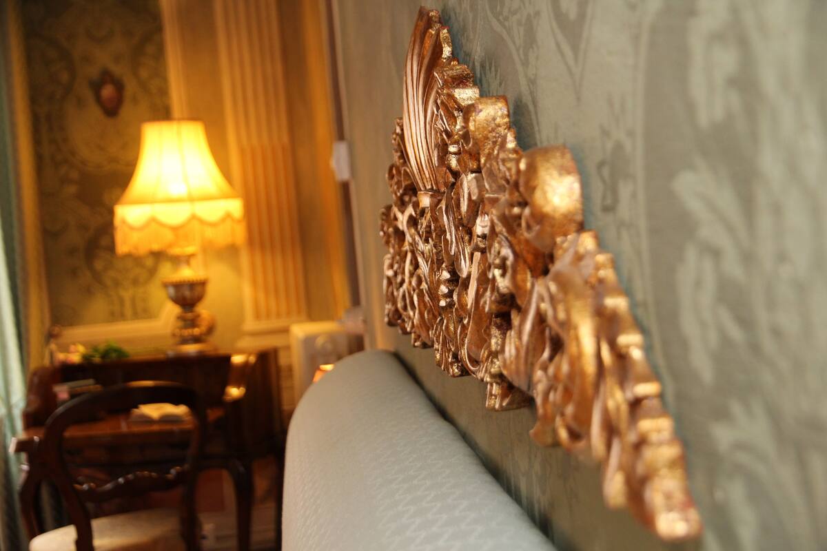 A room with a decorative wall panel, a lamp, and a chair.