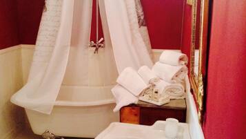A bathroom with a clawfoot bathtub, a white sink, and a vanity mirror.