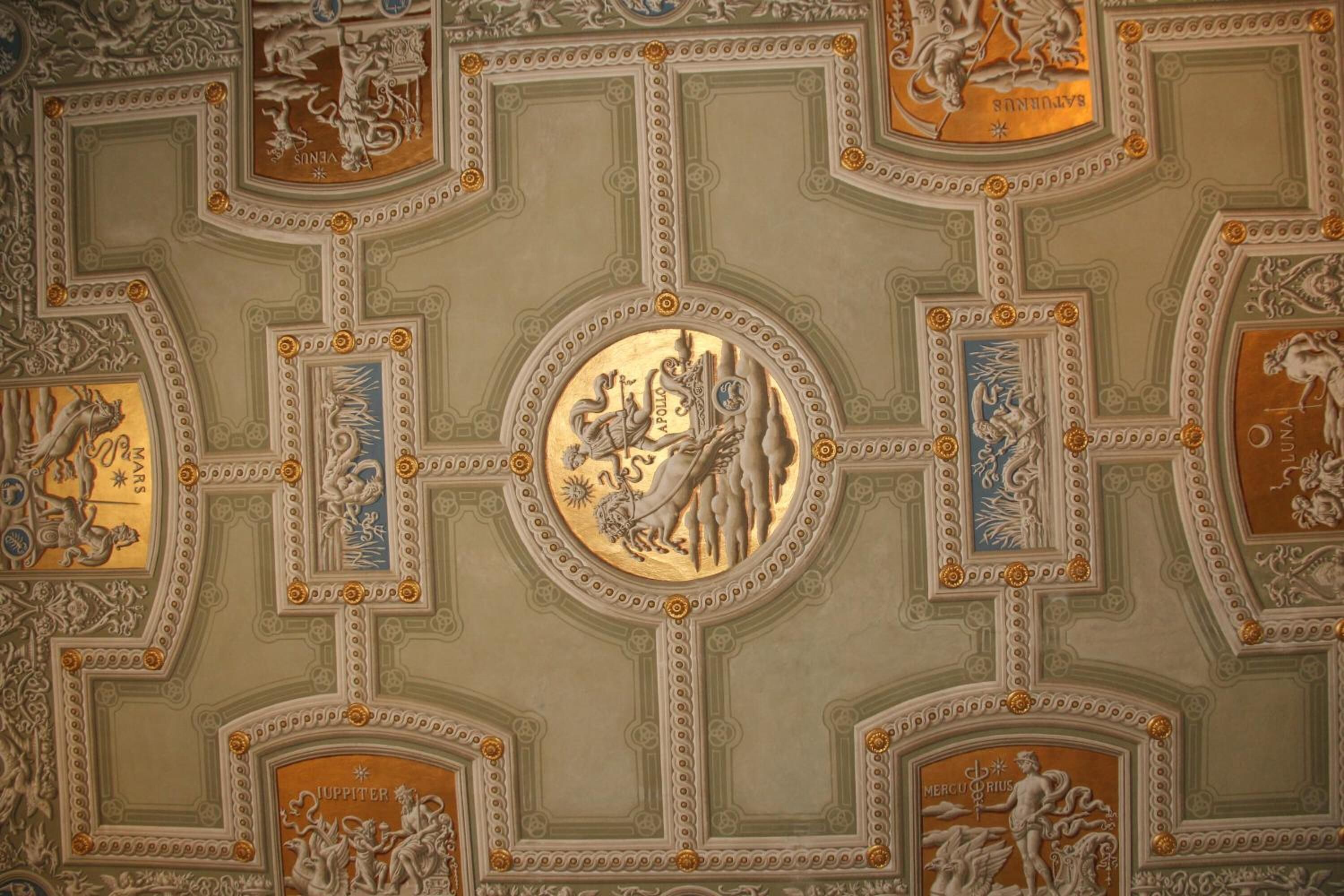 Un techo con intrincados diseños geométricos y esculturas clásicas.