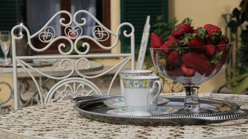 A table with a decorative metal tray, a glass bowl of strawberries, and a floral-patterned cup and saucer.