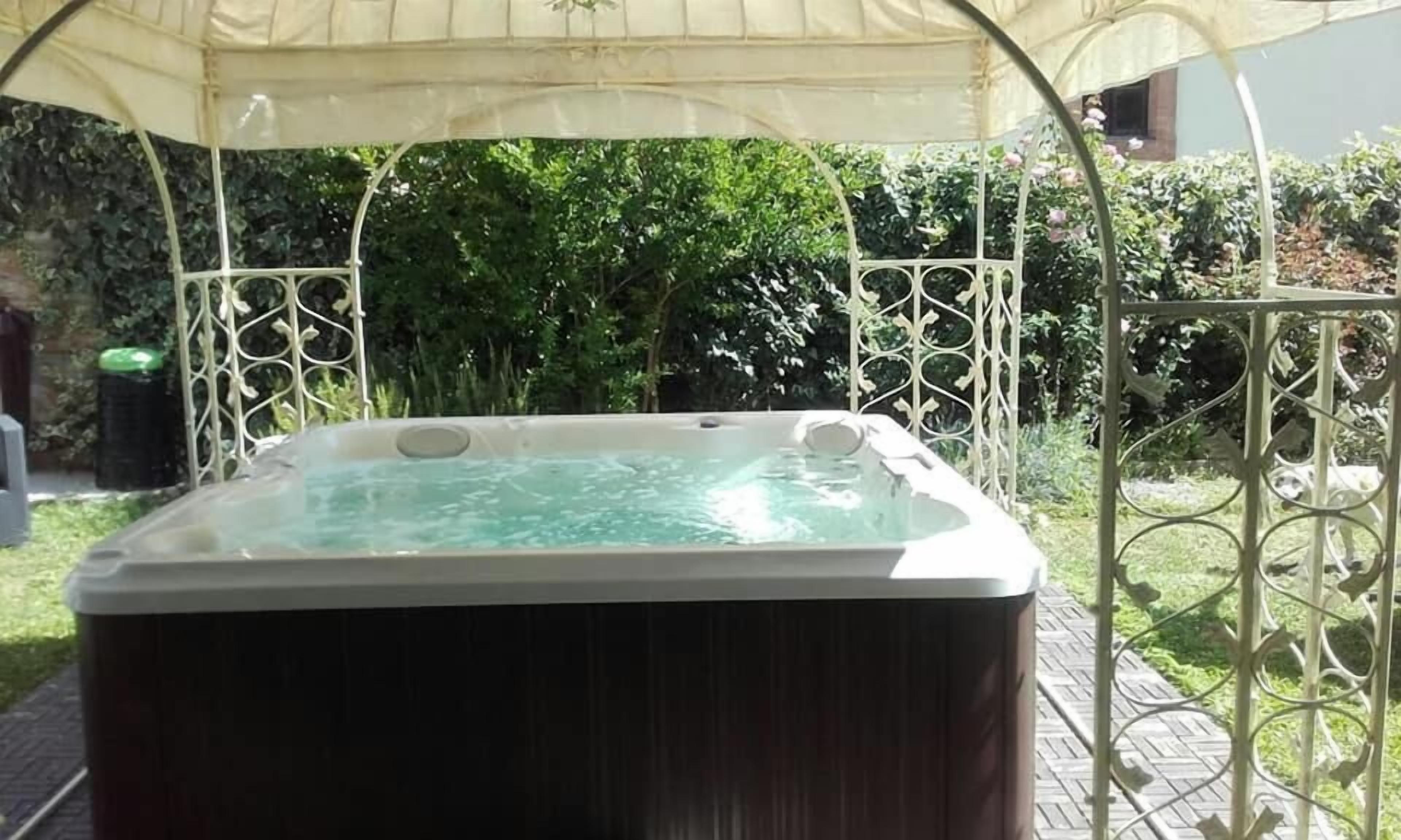 A hot tub under a canopy in a garden setting.