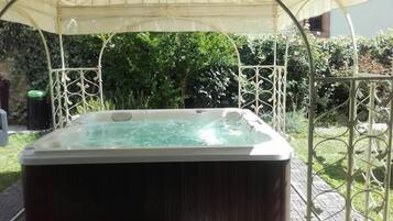 A hot tub under a canopy in a garden setting.