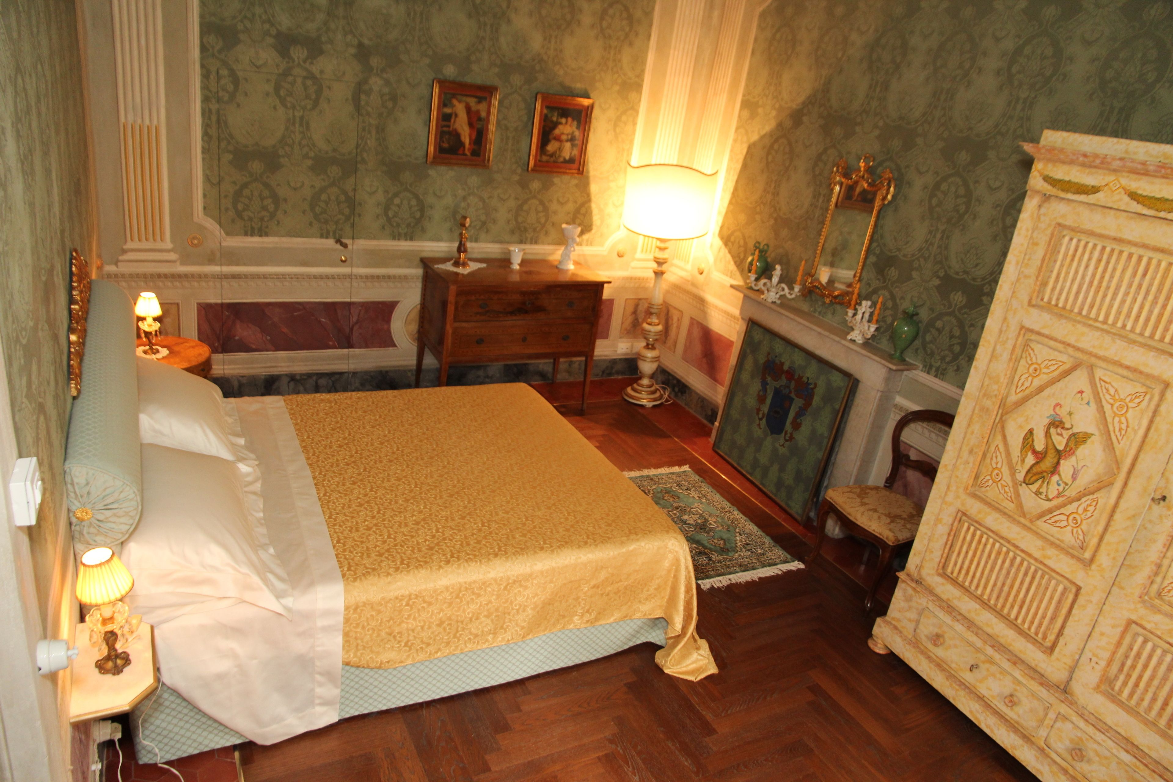 Un dormitorio con cama, cómoda, mesita de noche, lámpara y espejo.