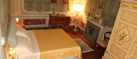 A bedroom with a bed, dresser, nightstand, lamp, and a mirror.