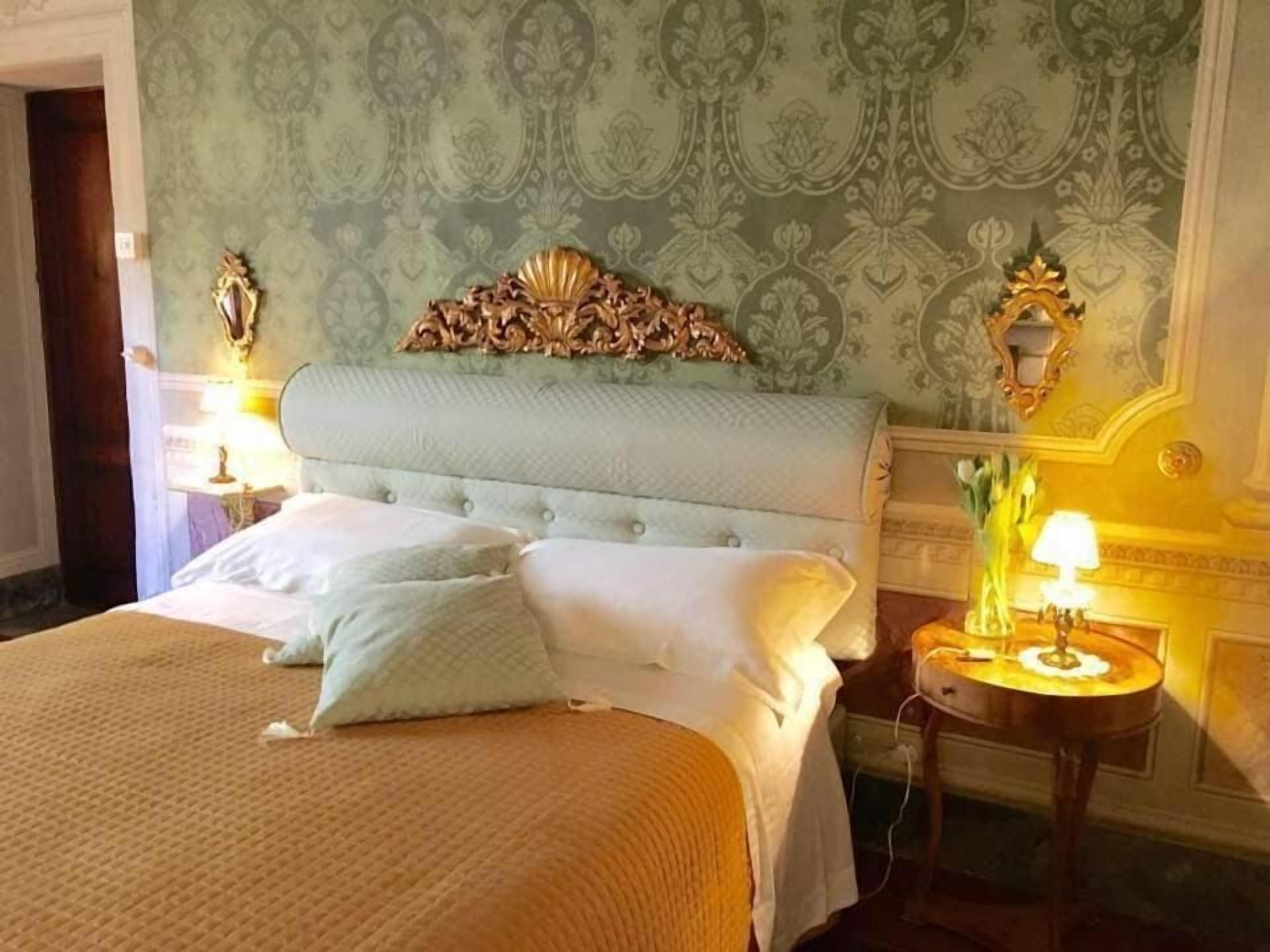 Ein Hotelzimmer mit einem großen Bett, einem verzierten Kopfteil und zwei Nachttischlampen.