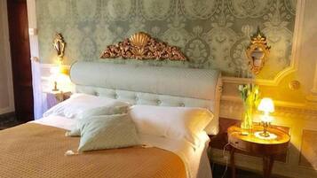 Ein Hotelzimmer mit einem großen Bett, einem verzierten Kopfteil und zwei Nachttischlampen.