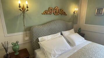 A bedroom with a patterned headboard, two bedside lamps, a green vase, and a bed with white bedding.