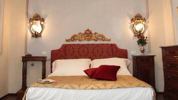 A bedroom with a large bed, ornate headboard, two wall sconces, a nightstand, a dresser, and a patterned rug.