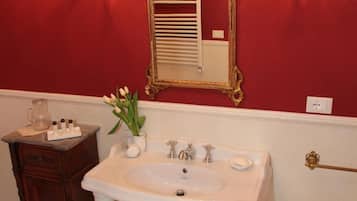 Un bagno con un lavandino bianco, uno specchio con cornice dorata e un lampadario.