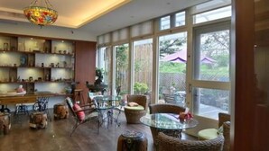 Una habitación amplia con un gran ventanal, muebles de mimbre y un candelabro decorativo.