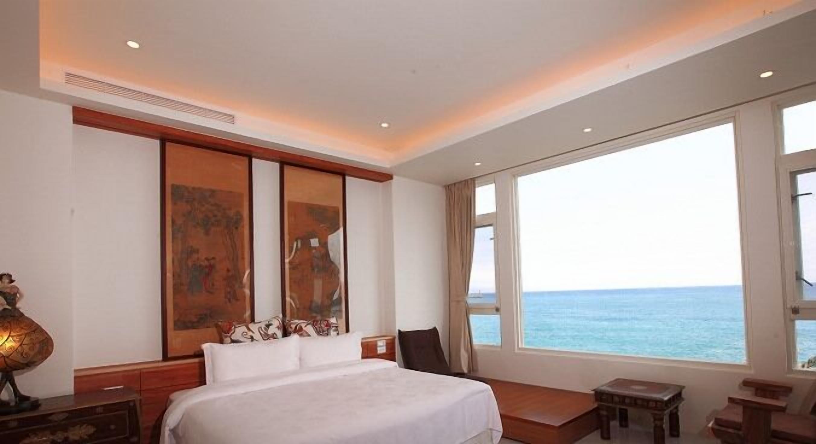 Une chambre d’hôtel avec un grand lit, une vue sur la mer et des œuvres d’art accrochées au mur.