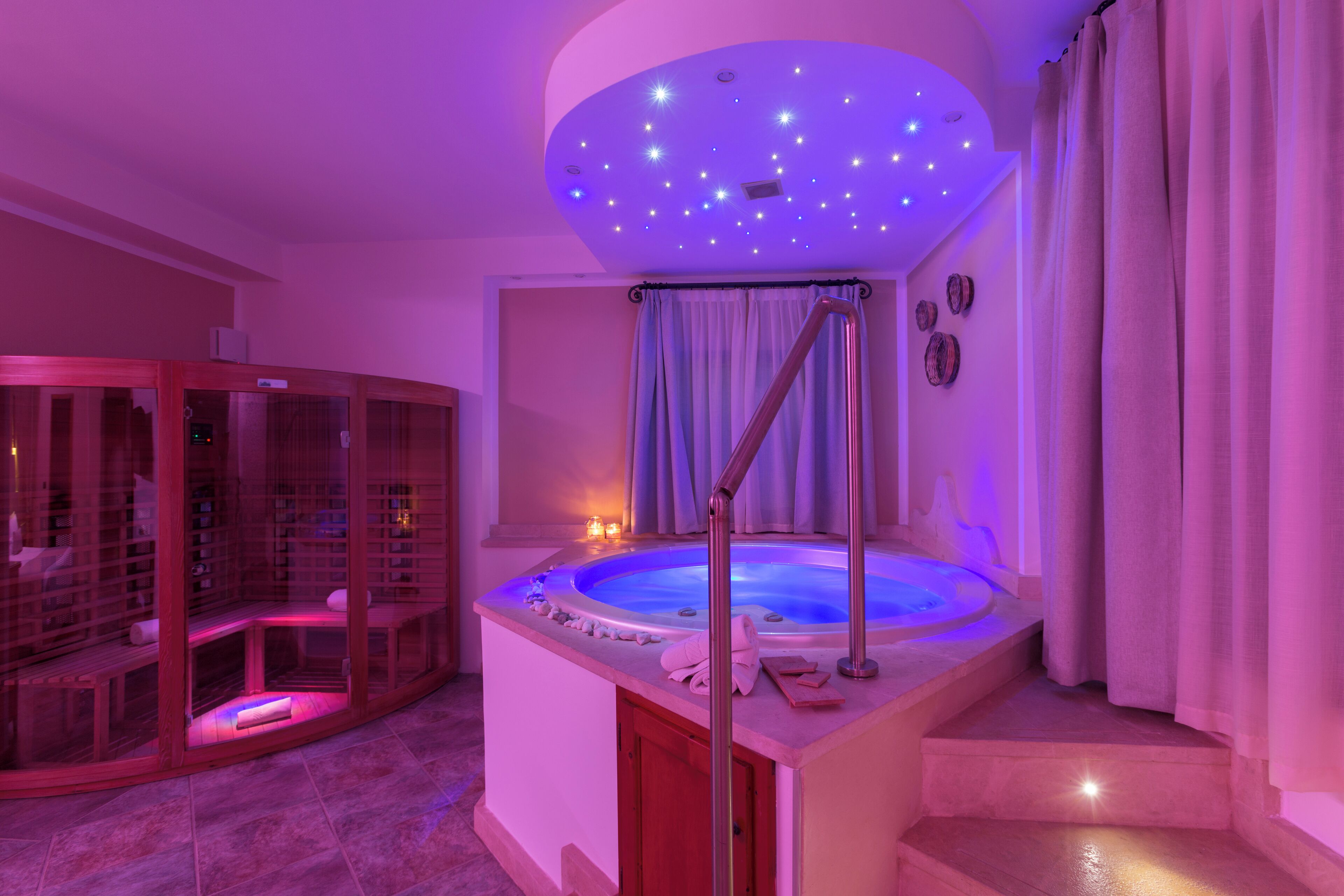 Un espace de bien-être comprenant un jacuzzi, une paroi de verre et un plafond orné de lumières en forme d’étoiles.