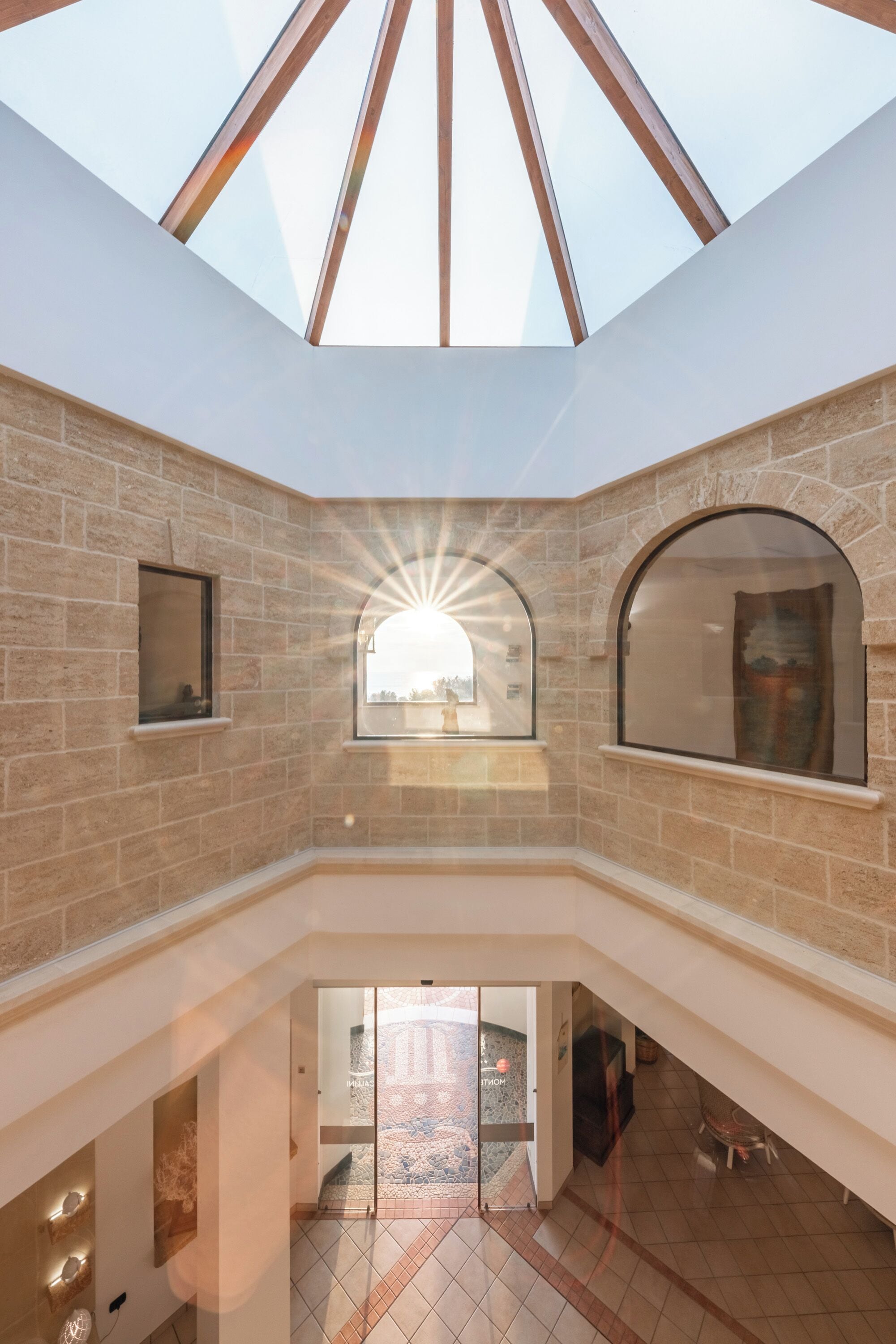 Un intérieur spacieux avec un plafond haut et une lucarne, des murs en pierre et une vue sur l’extérieur.