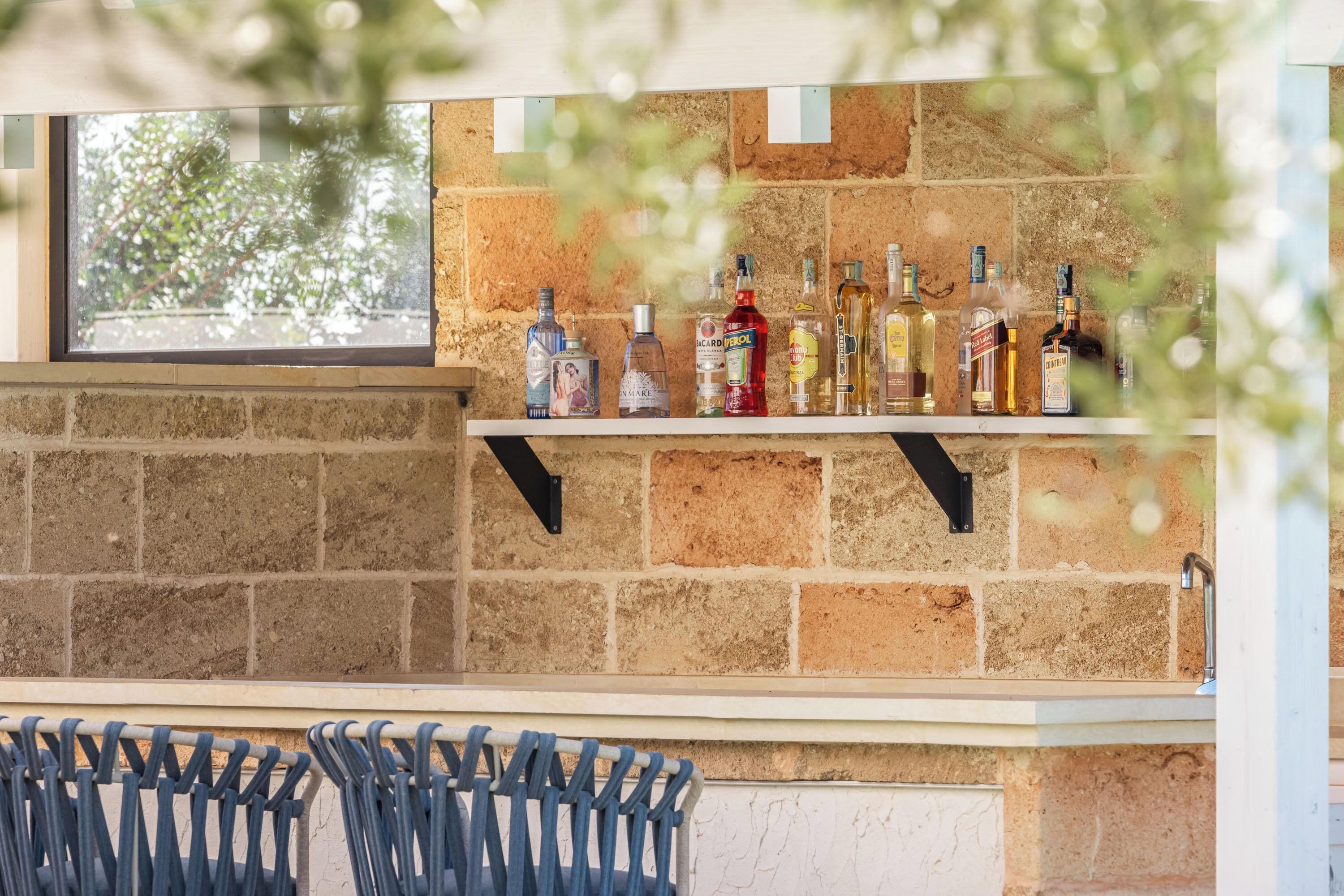 A bar area with a brick wall and shelves holding various bottles.