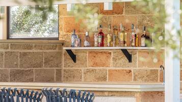 A bar area with a brick wall and shelves holding various bottles.