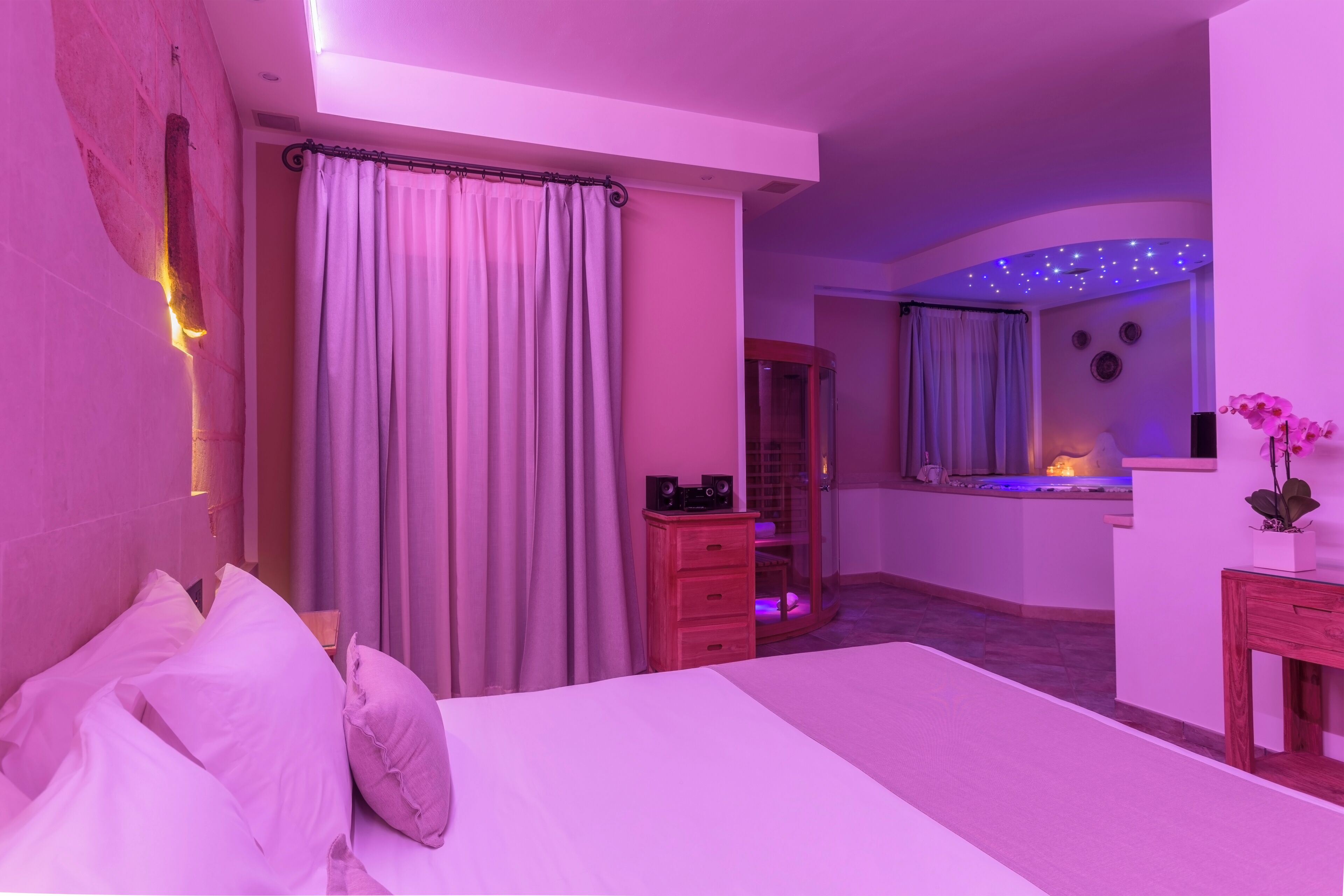Een slaapkamer met een bed, gordijnen, een dressoir, een kaptafel en een spiegel.