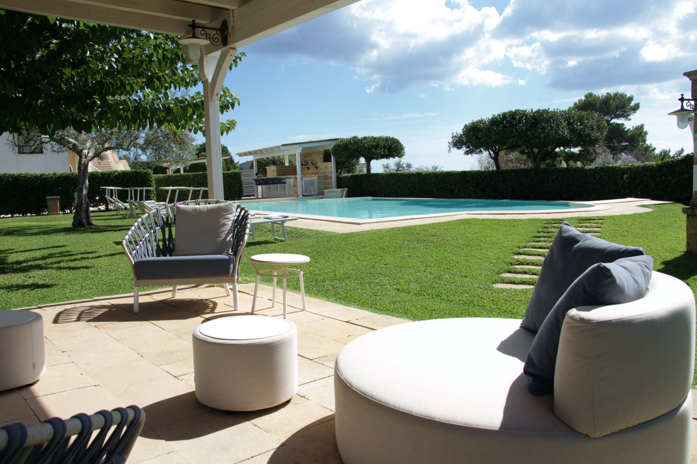 A patio with outdoor furniture, a swimming pool, and a well-maintained lawn.