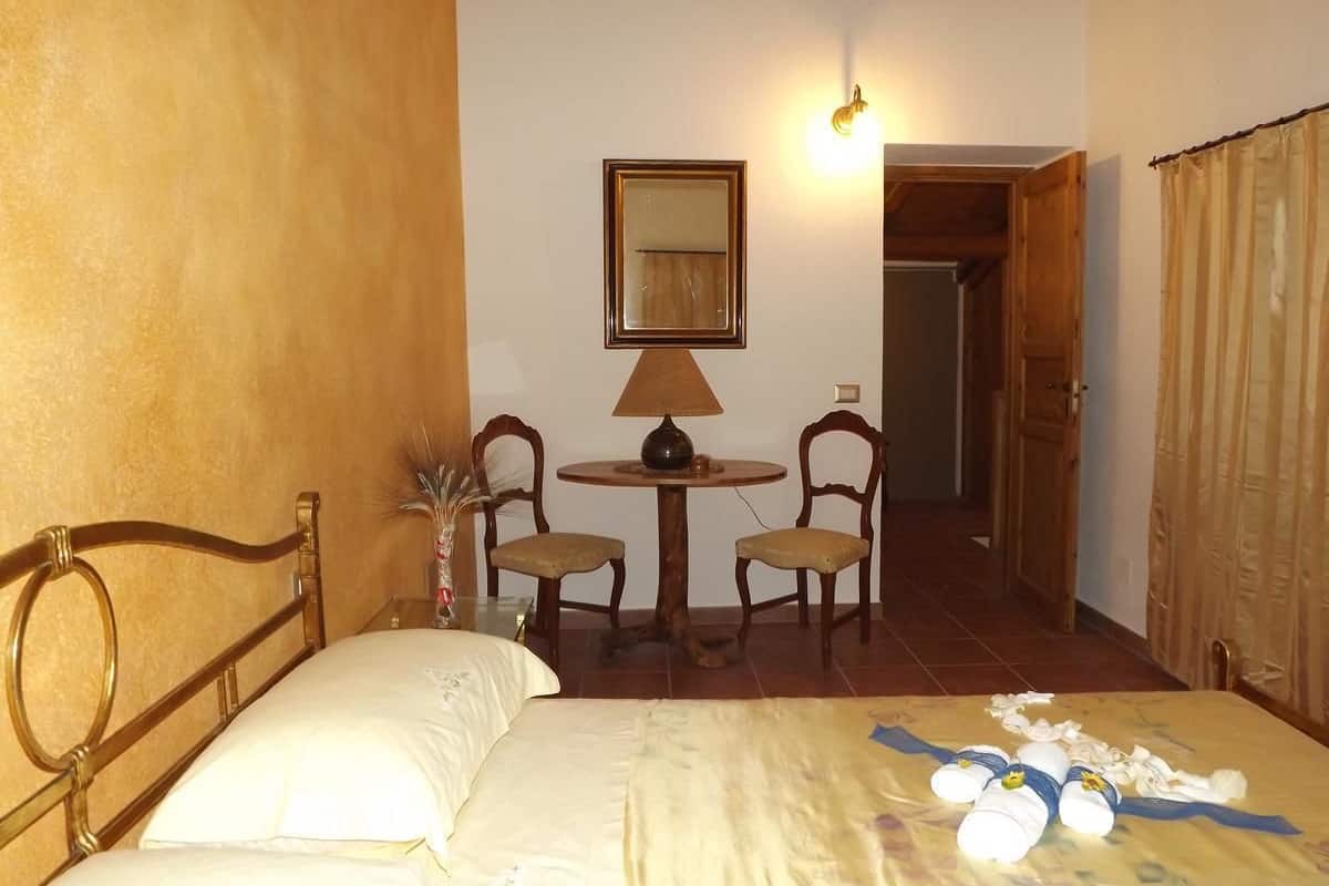 Un dormitorio con cama, una mesita con sillas, una lámpara y un espejo en la pared.