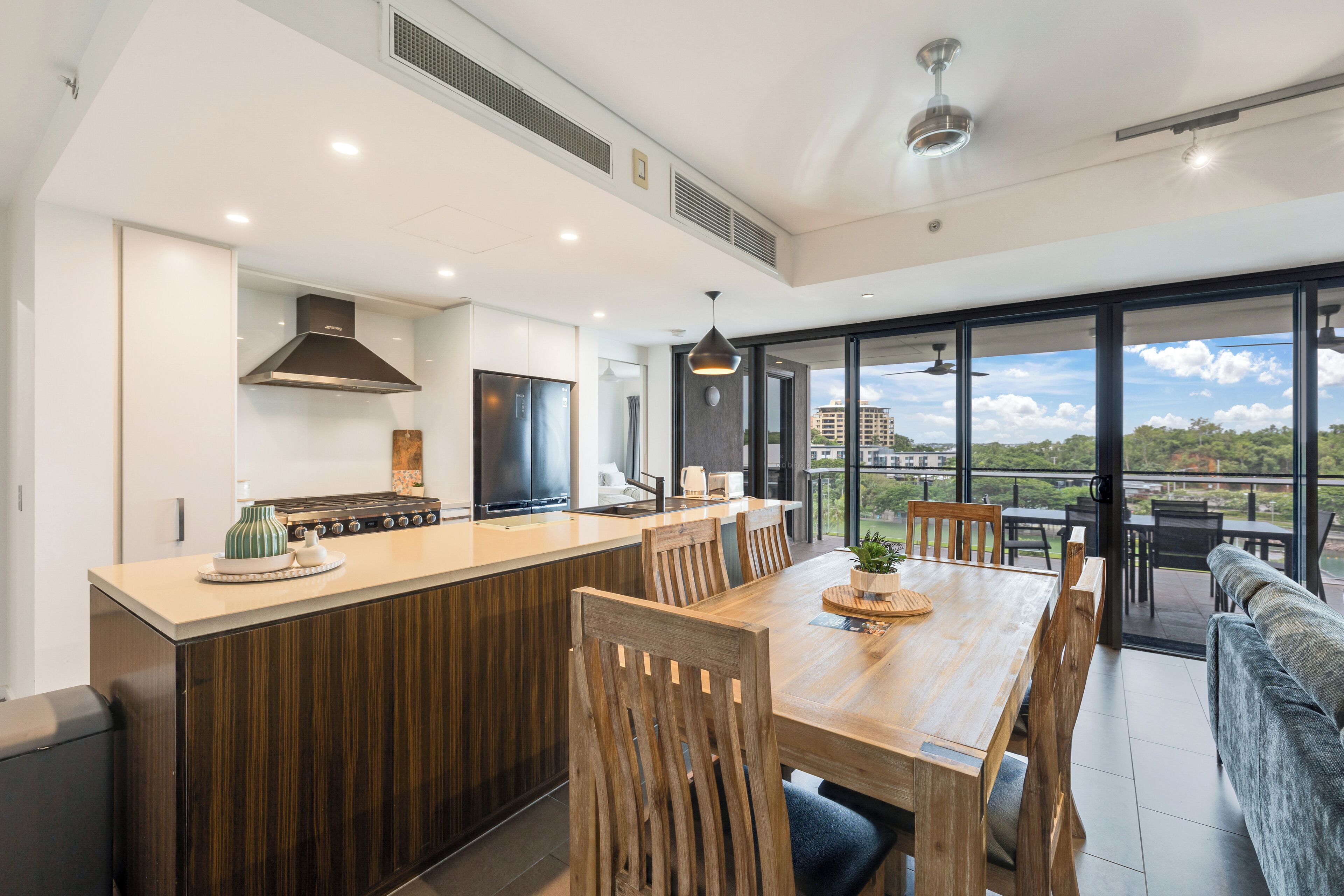 Une cuisine moderne avec un îlot central, des chaises en bois et une table à manger.
