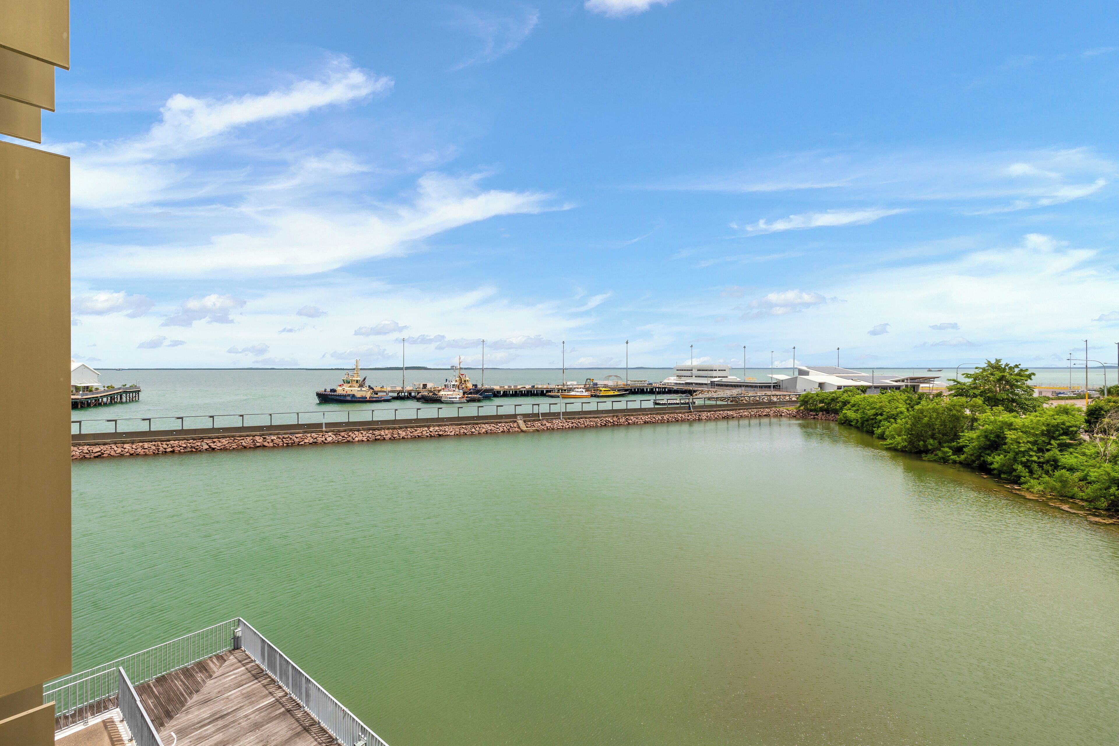 Vista al agua con un muelle, barcos y edificios industriales.