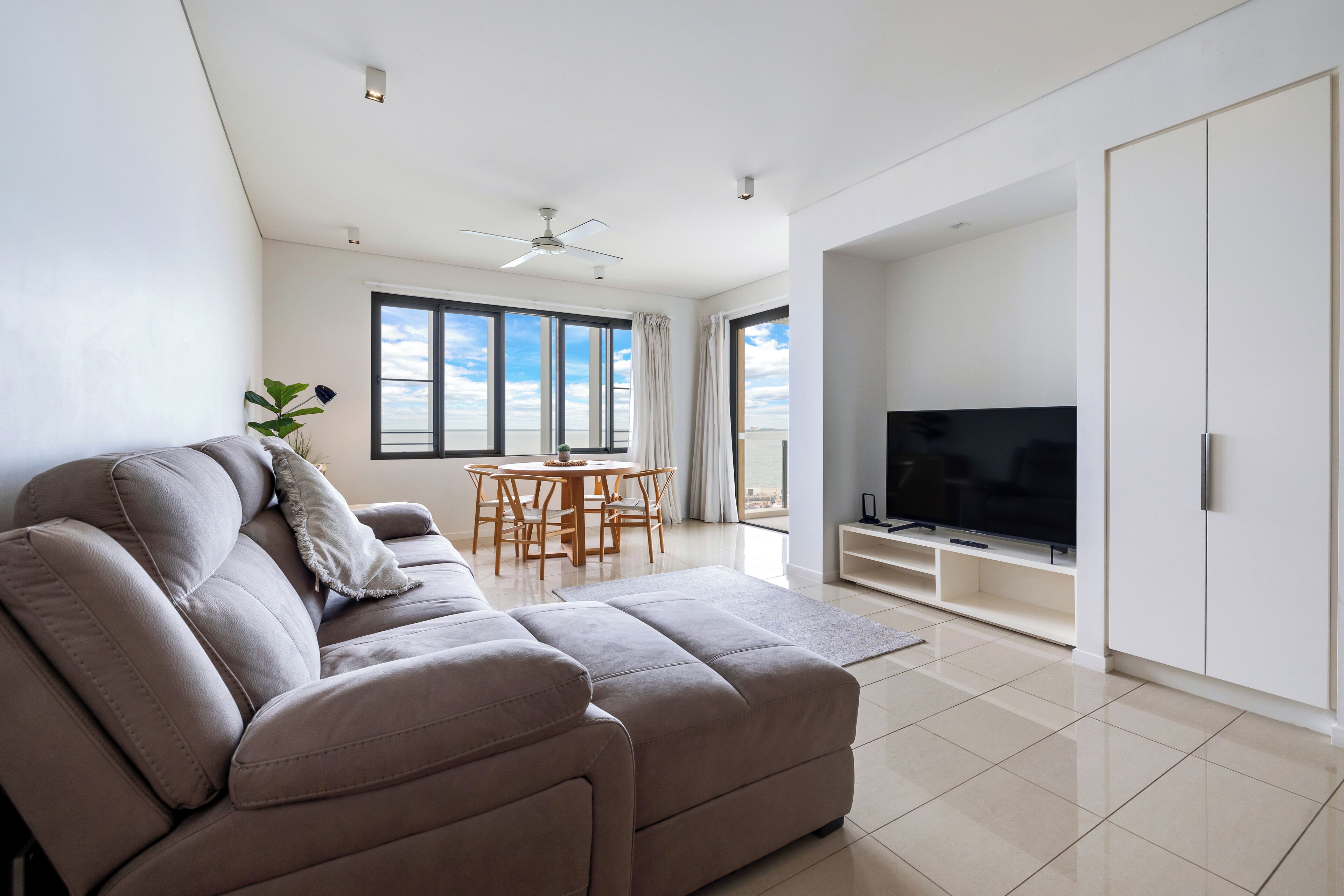 A modern living room with a sofa, TV, and dining area.