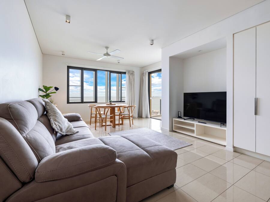 A modern living room with a sofa, TV, and dining area.