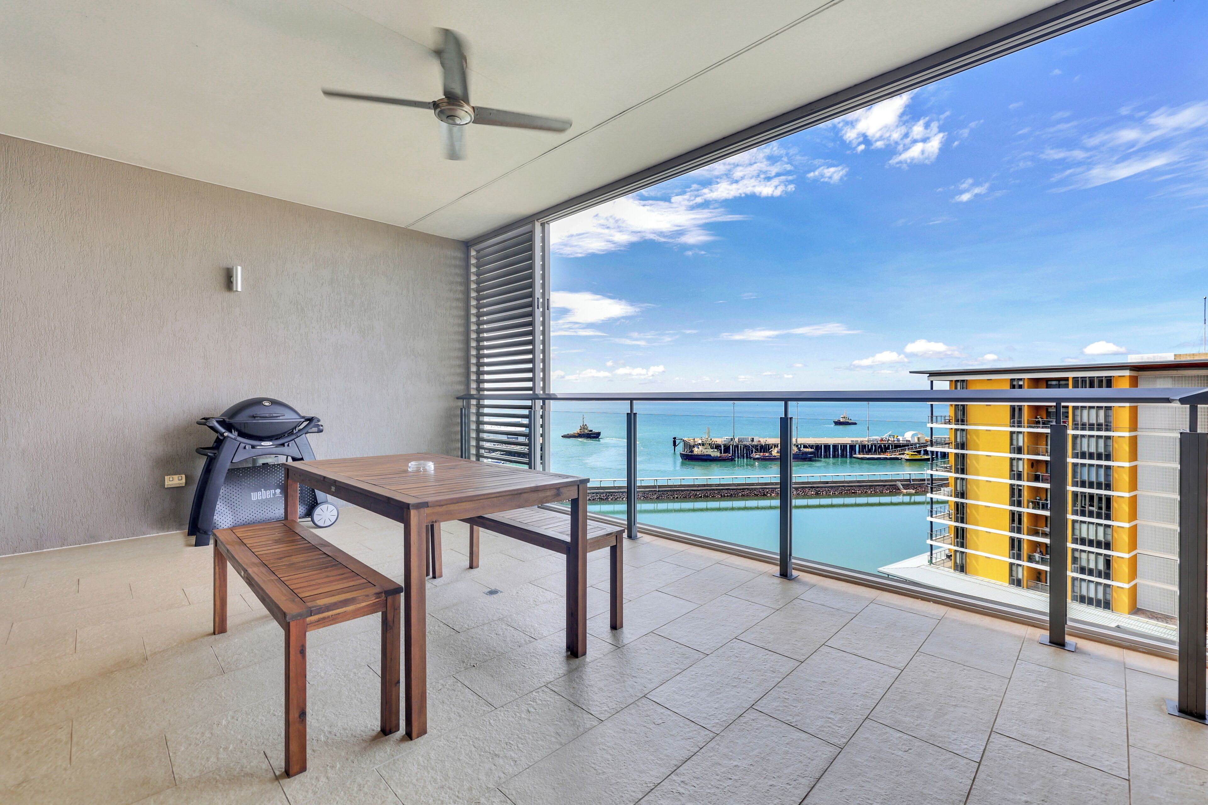 Un balcón con vista al mar, una parrilla y una mesa.