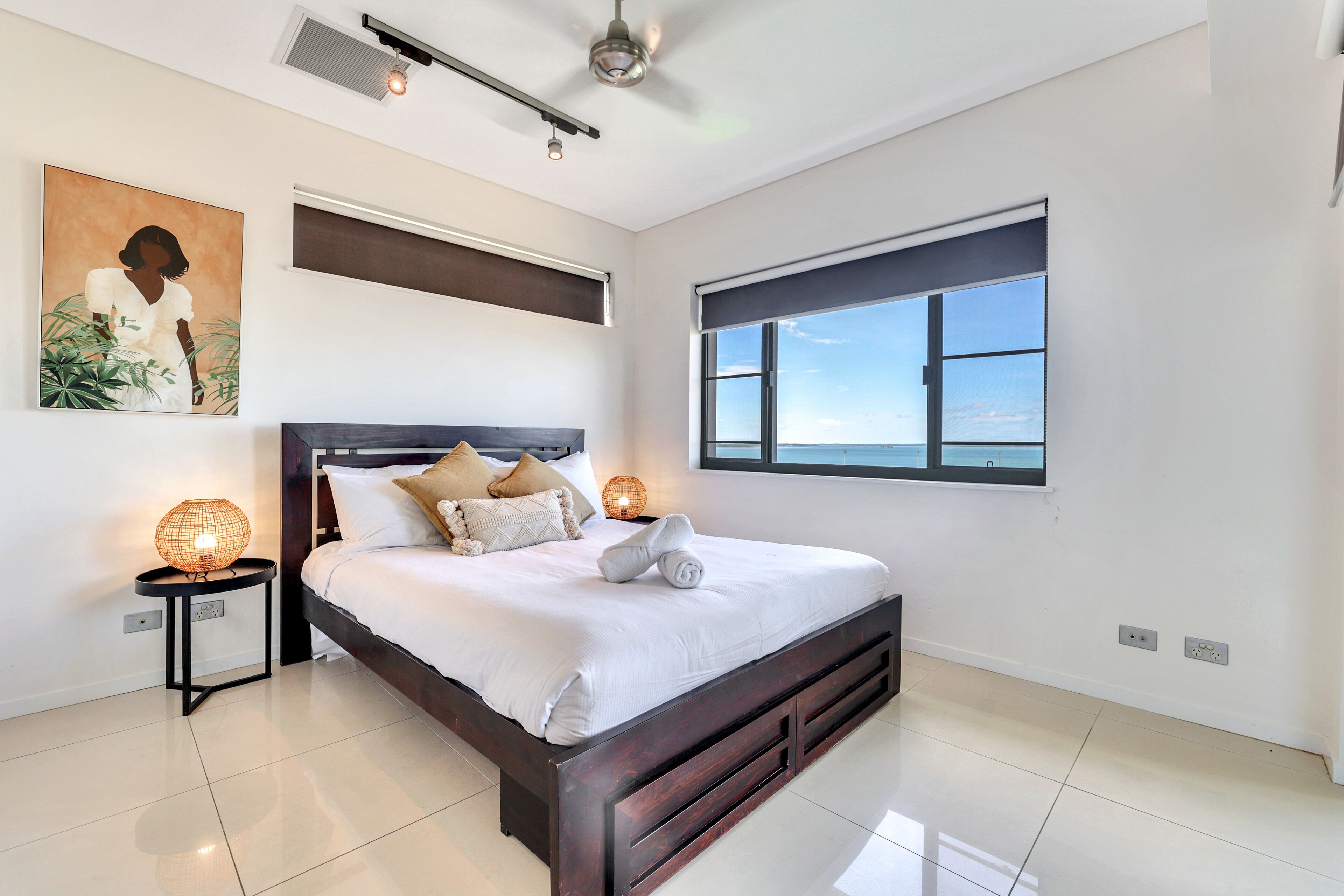 Un dormitorio moderno con una cama grande, un ventilador de techo, una ventana con vistas y un aire acondicionado de pared.