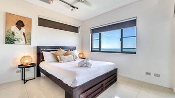 Un dormitorio moderno con una cama grande, un ventilador de techo, una ventana con vistas y un aire acondicionado de pared.