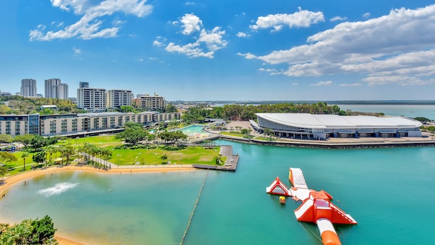 Vista al agua con un estadio grande, una piscina y varios edificios altos.