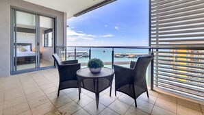 Un balcón con vistas al mar, una cama y una mesa con sillas.