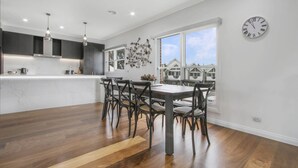 A modern kitchen with dark cabinets, a marble countertop, and pendant lighting. - The Apartment, Metung (Metung)